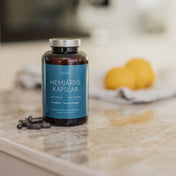 En burk av järntillskottet Feméa hemjärnskapslar i ett ljust kök med några kapslar framför burken