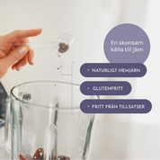 Hand häller ner hemjärnspulver från en skopa i en smoothie och texter som beskriver järnpulvret som glutenfritt, fritt från tillsatser och naturligt hemjärn